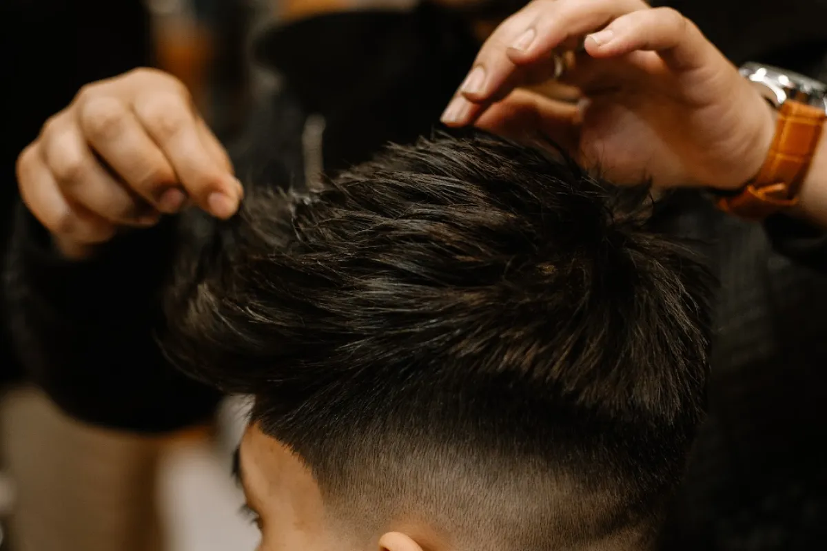 A barber at DeezyCuts shaping a textured haircut