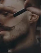 A barber shaping a beard with a razor